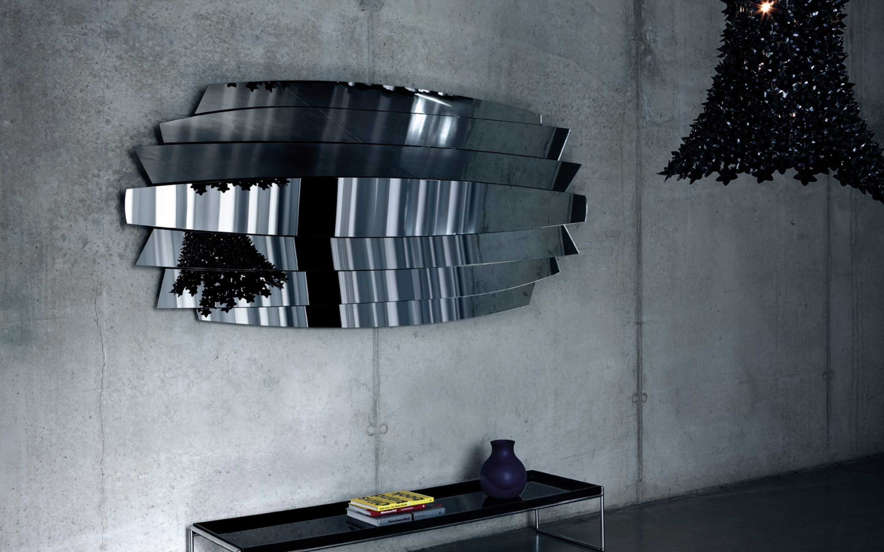 An oversized sculptural Deknudt mirror on a concrete wall